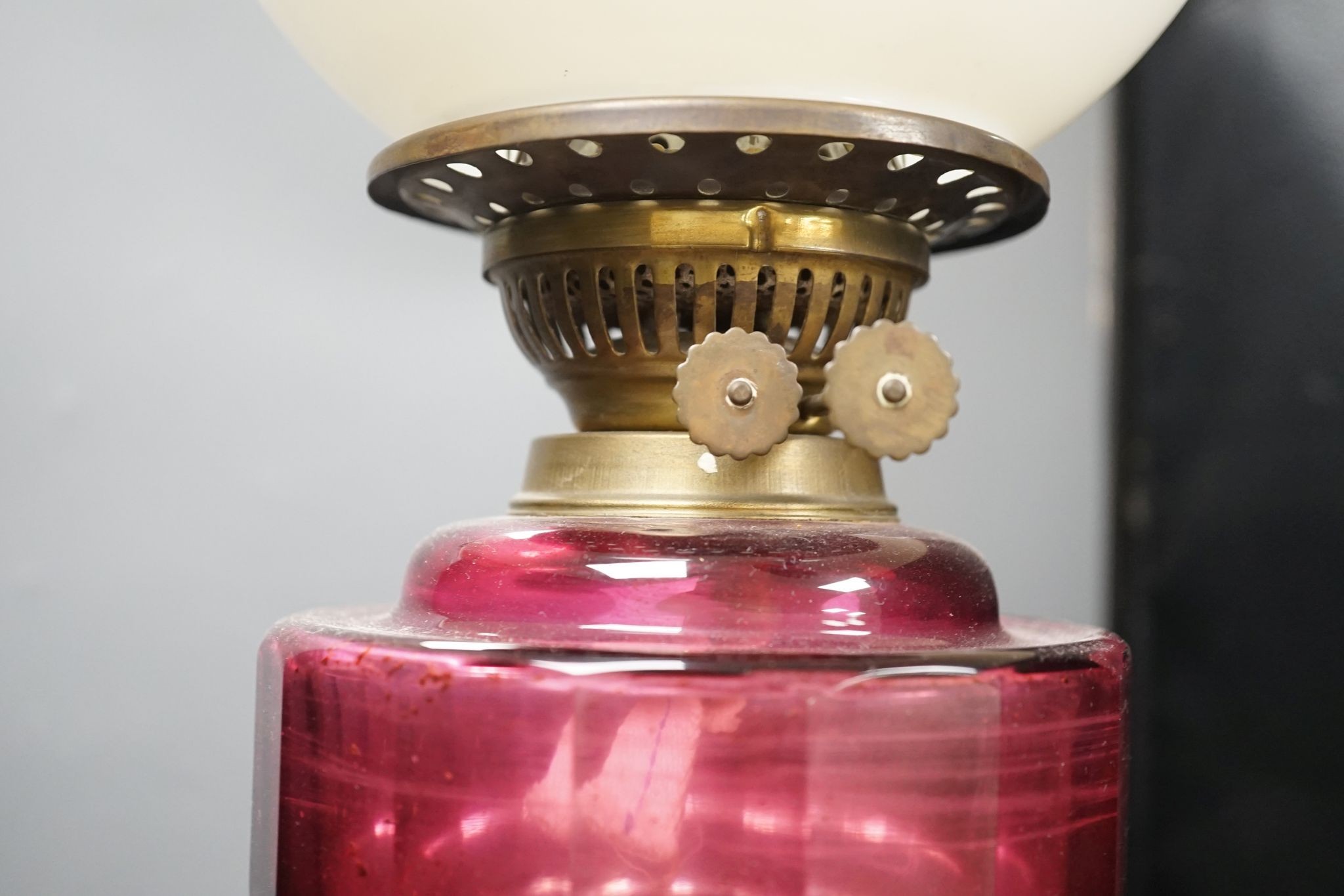 A Victorian brass and cranberry glass oil lamp, 78 cms high.